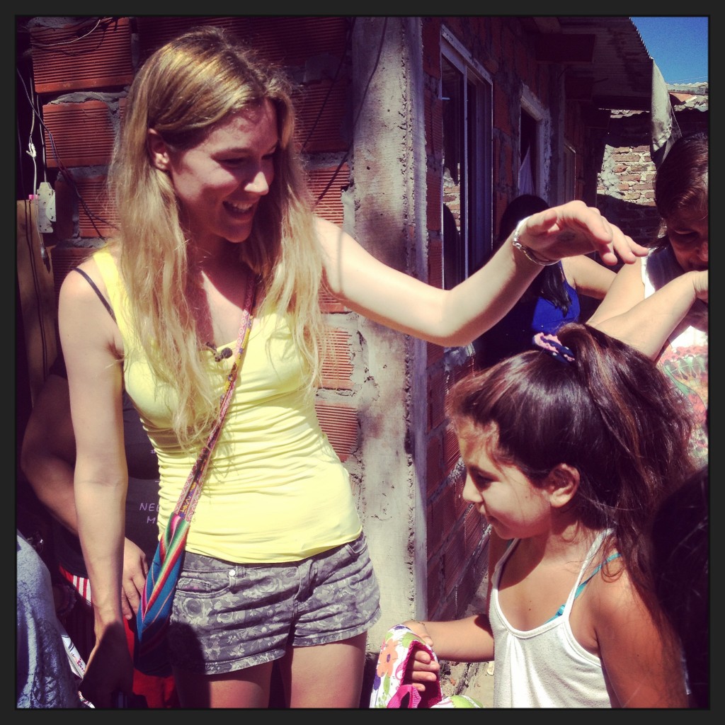 Joss Stone gives out a rucksack to a young girl in Villa La Cárcova. Ph: Sorrel Moseley-Williams